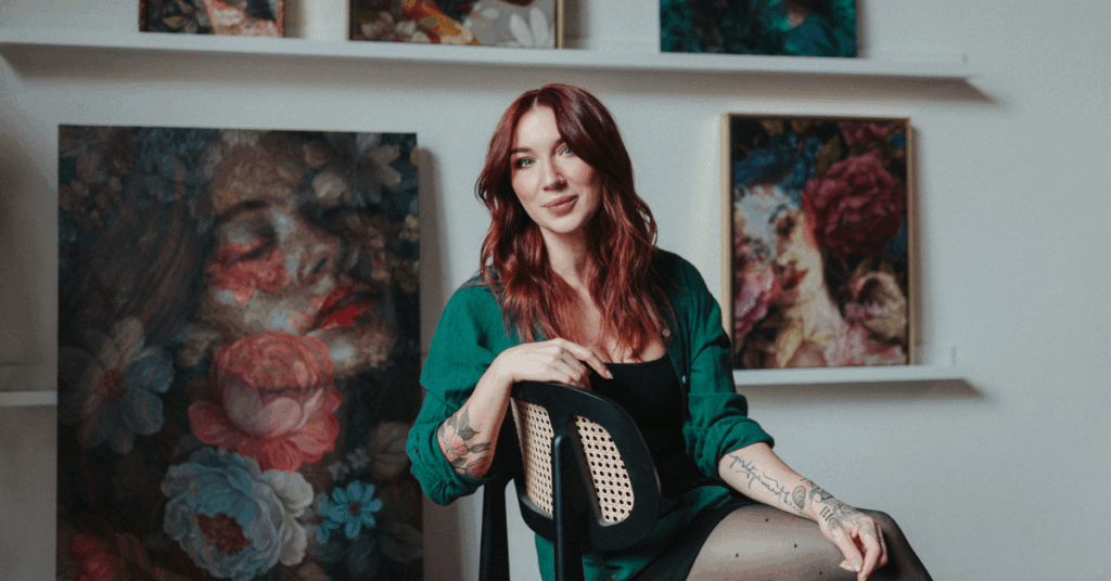Artist Jess Currier sitting in studio with her oil paintings in the background