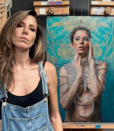 Shana Levenson in denim overalls standing with her ornate self-portrait painting highlighted by turquoise and pearl details.
